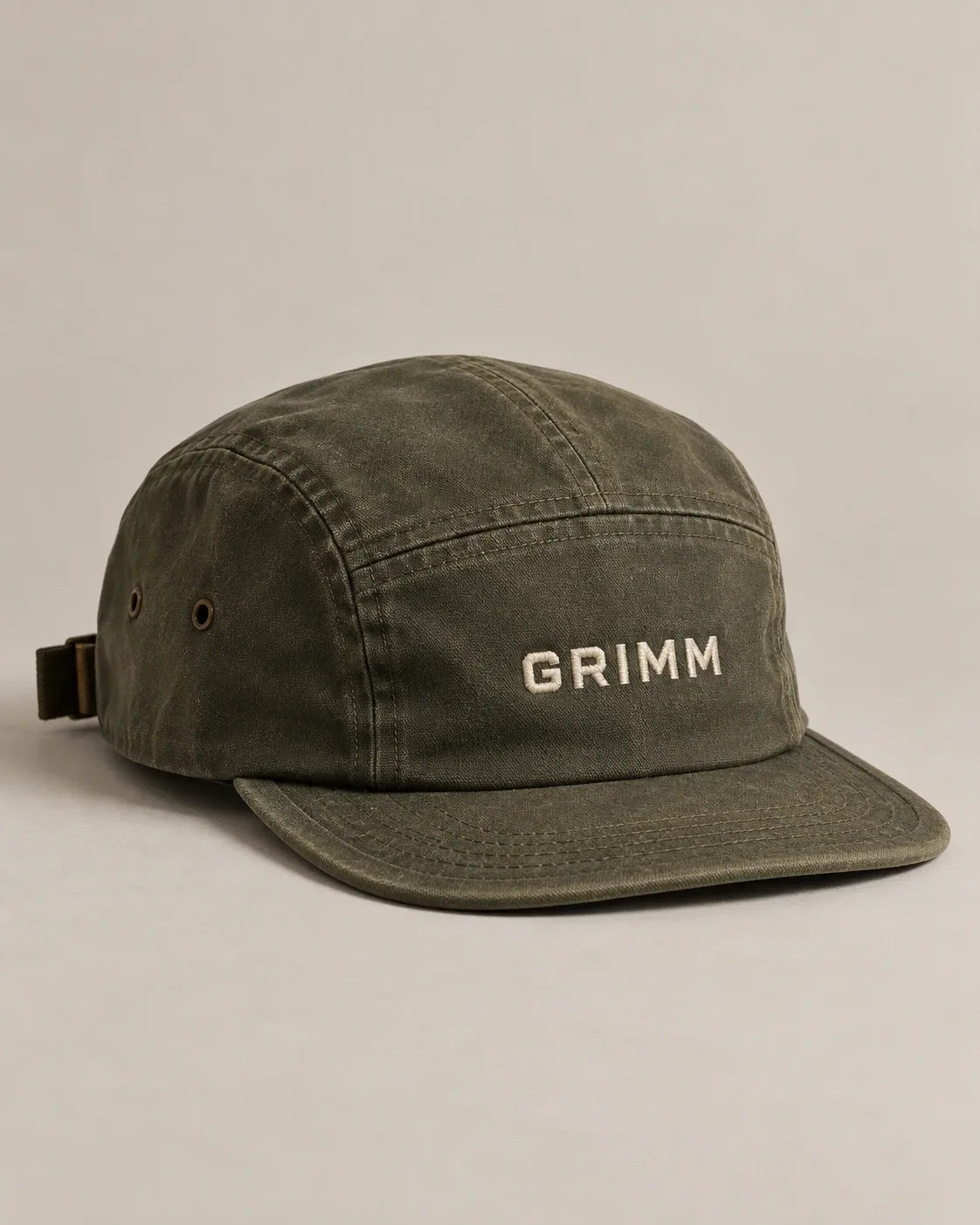 Washed olive 5-panel cap with GRIMM embroidered in cream on the front.